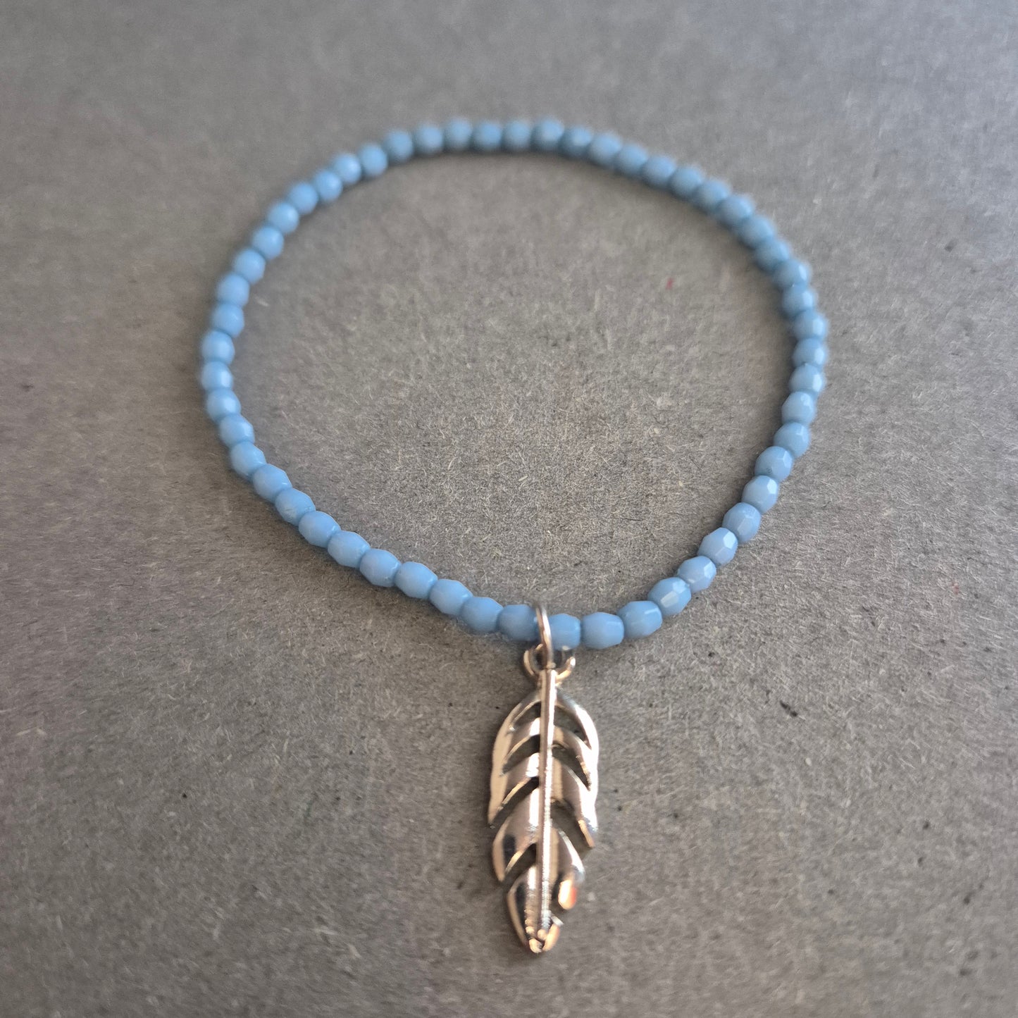 Zartes Perlenarmband in Hellblau mit Federanhänger – Boho trifft Minimalismus