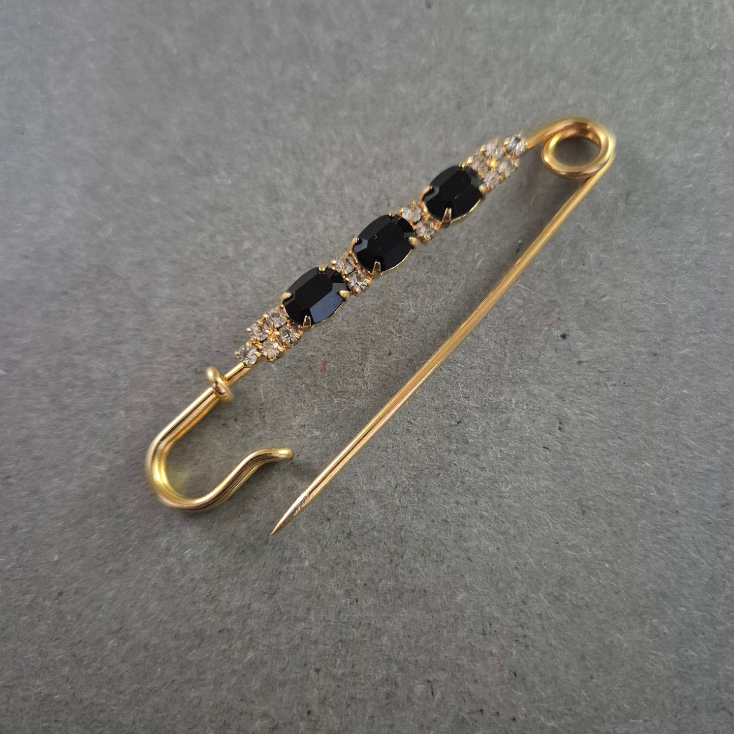 Elegante goldene Brosche – Sicherheitsnadel mit schwarzen Ziersteinen