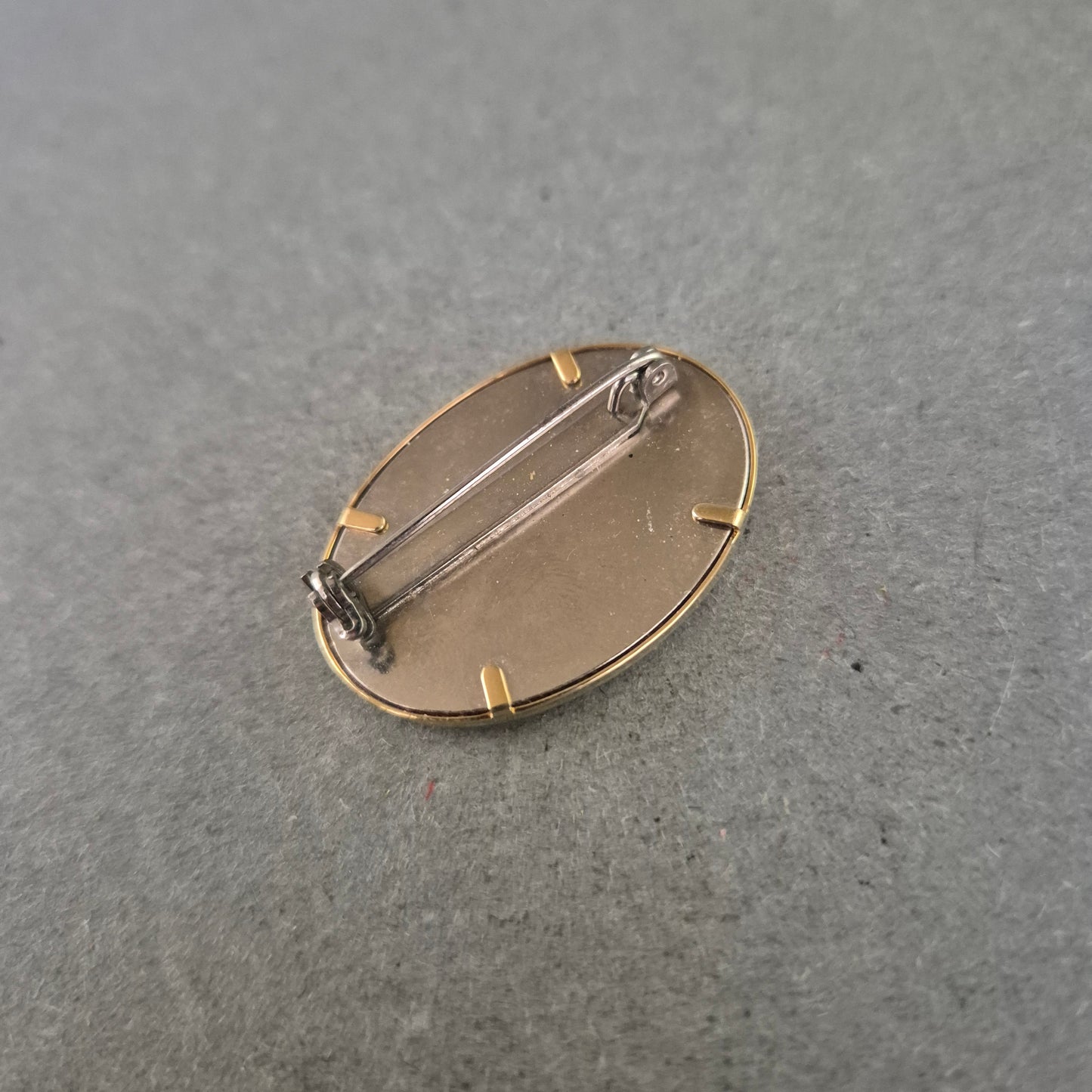 Ovale Brosche mit lila Stoffeinlage und goldener Handzeichnung