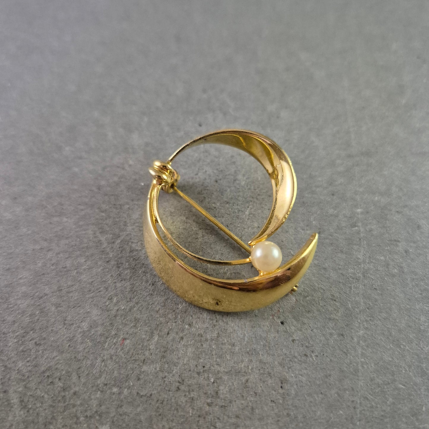 Elegante goldfarbene Brosche mit Perle im modernen Design