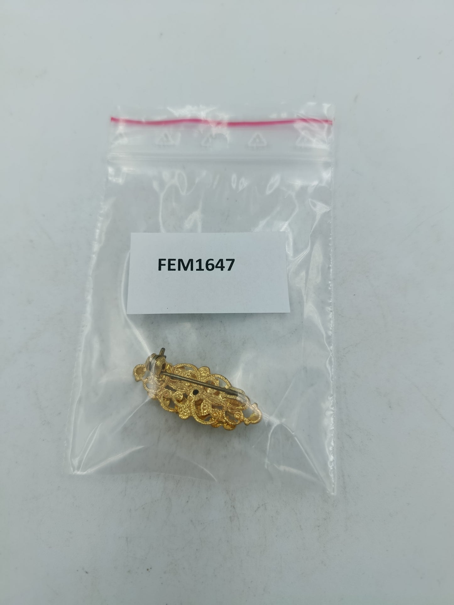 Goldfarbene Brosche mit filigranem Ornamentdesign und funkelnden Steinen