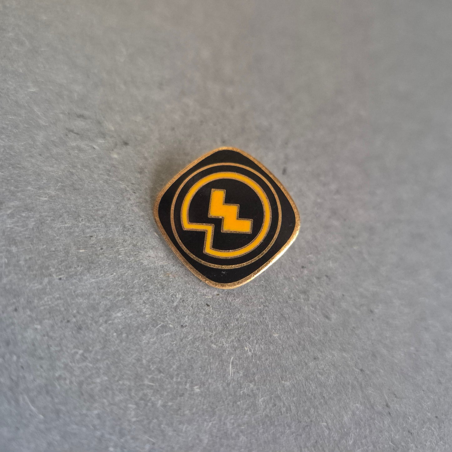 Vintage Emaille-Pin – Schwarzes Logo mit gelbem Blitzsymbol