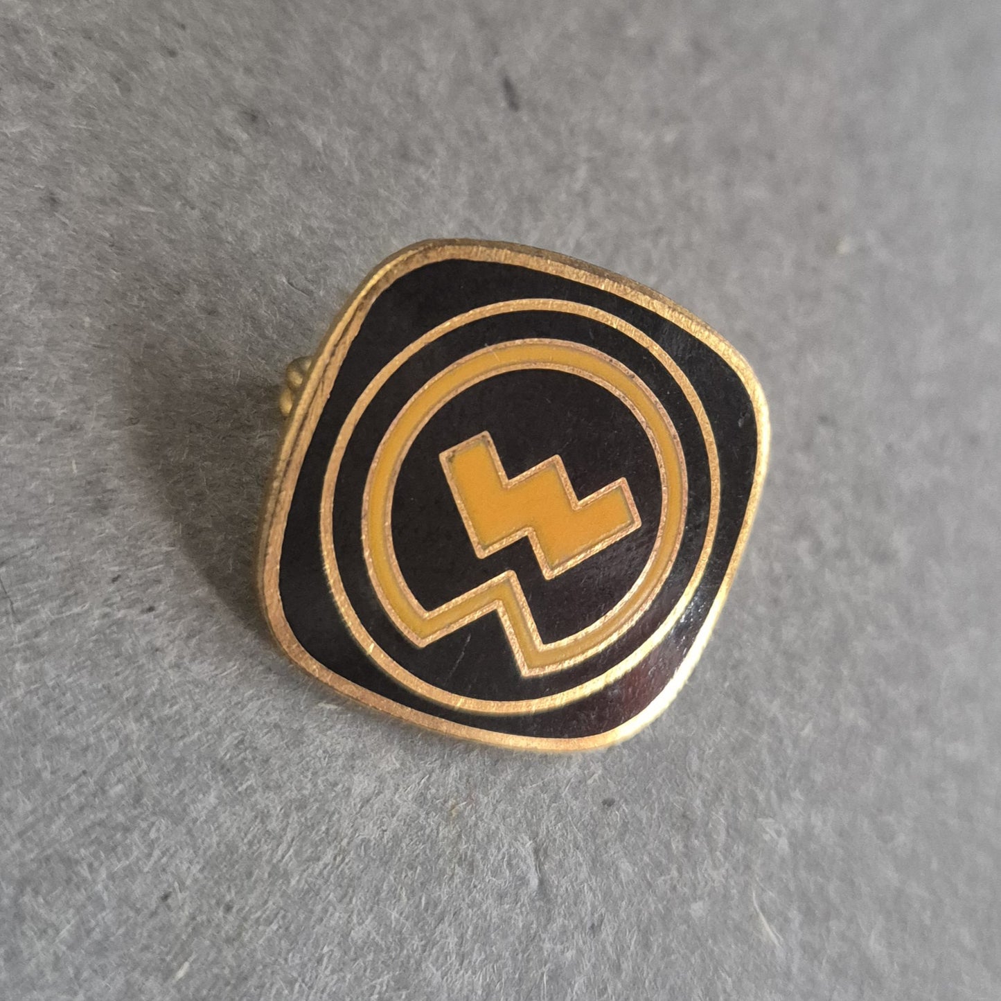 Vintage Emaille-Pin – Schwarzes Logo mit gelbem Blitzsymbol