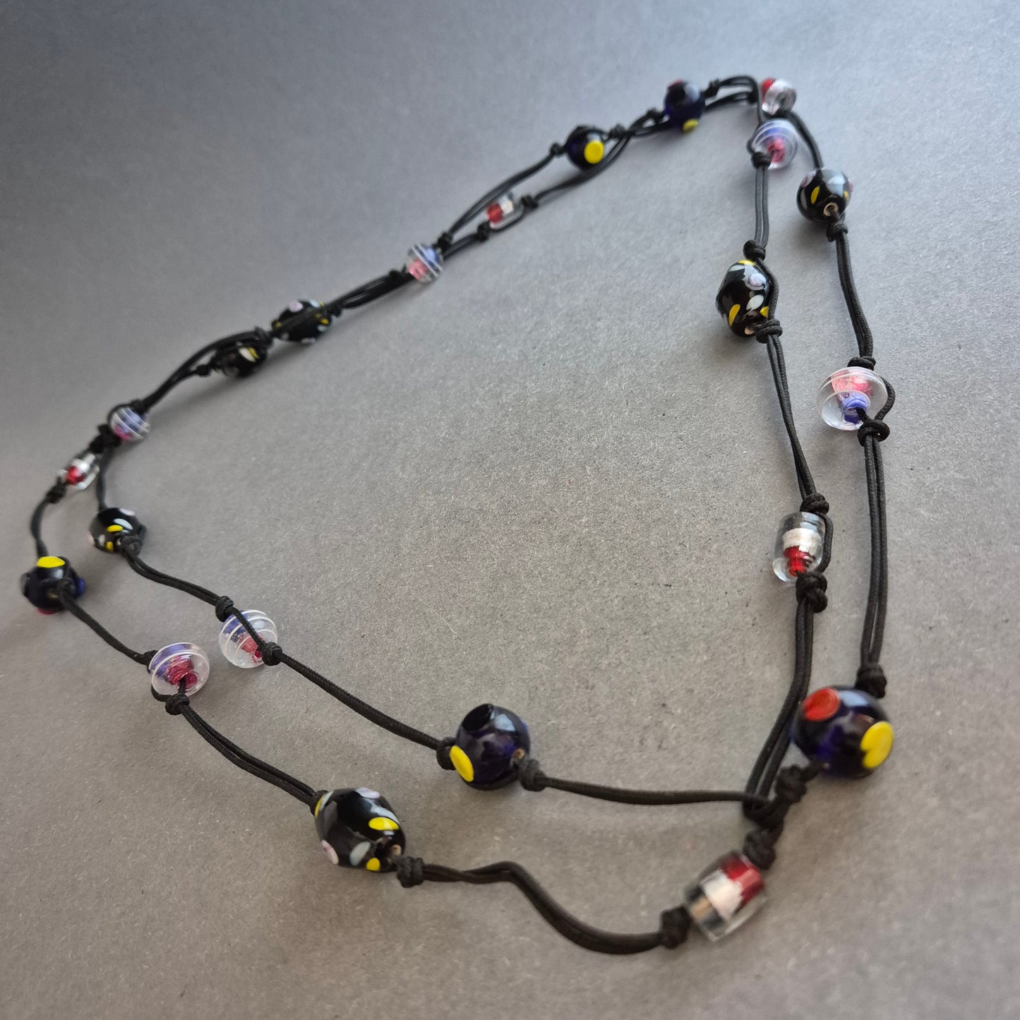 Zweireihige Kette mit bunten Glasperlen auf schwarzem Band