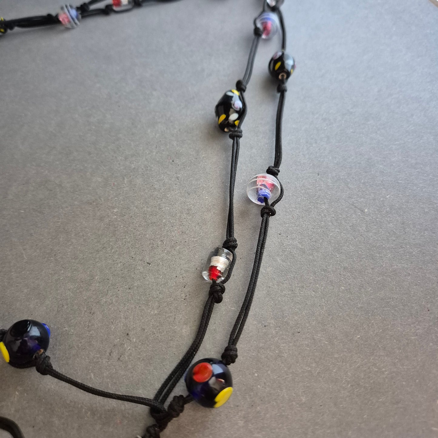 Zweireihige Kette mit bunten Glasperlen auf schwarzem Band