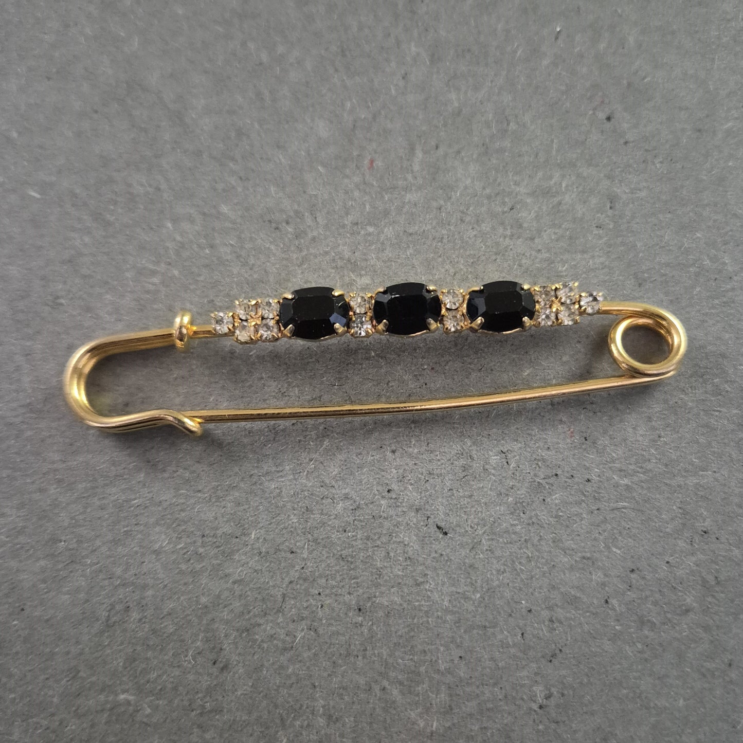 Elegante goldene Brosche – Sicherheitsnadel mit schwarzen Ziersteinen
