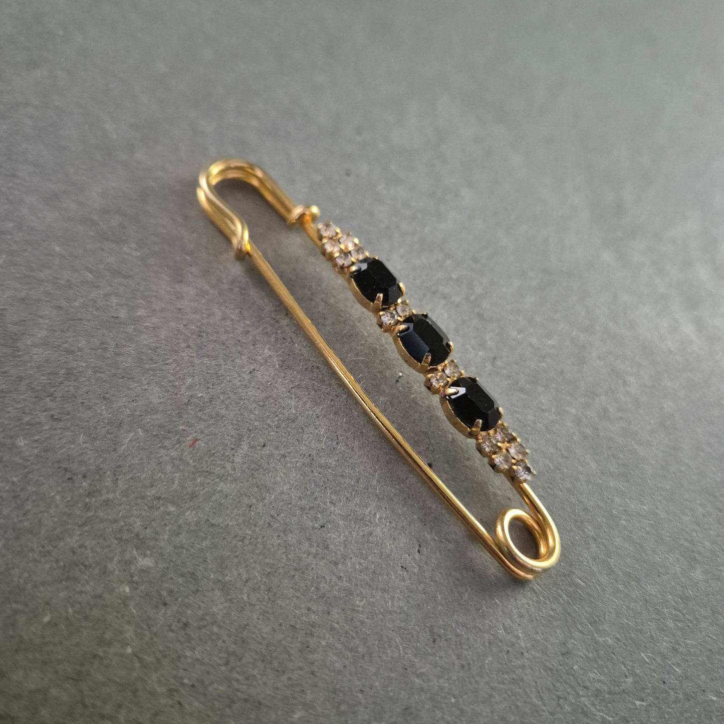 Elegante goldene Brosche – Sicherheitsnadel mit schwarzen Ziersteinen