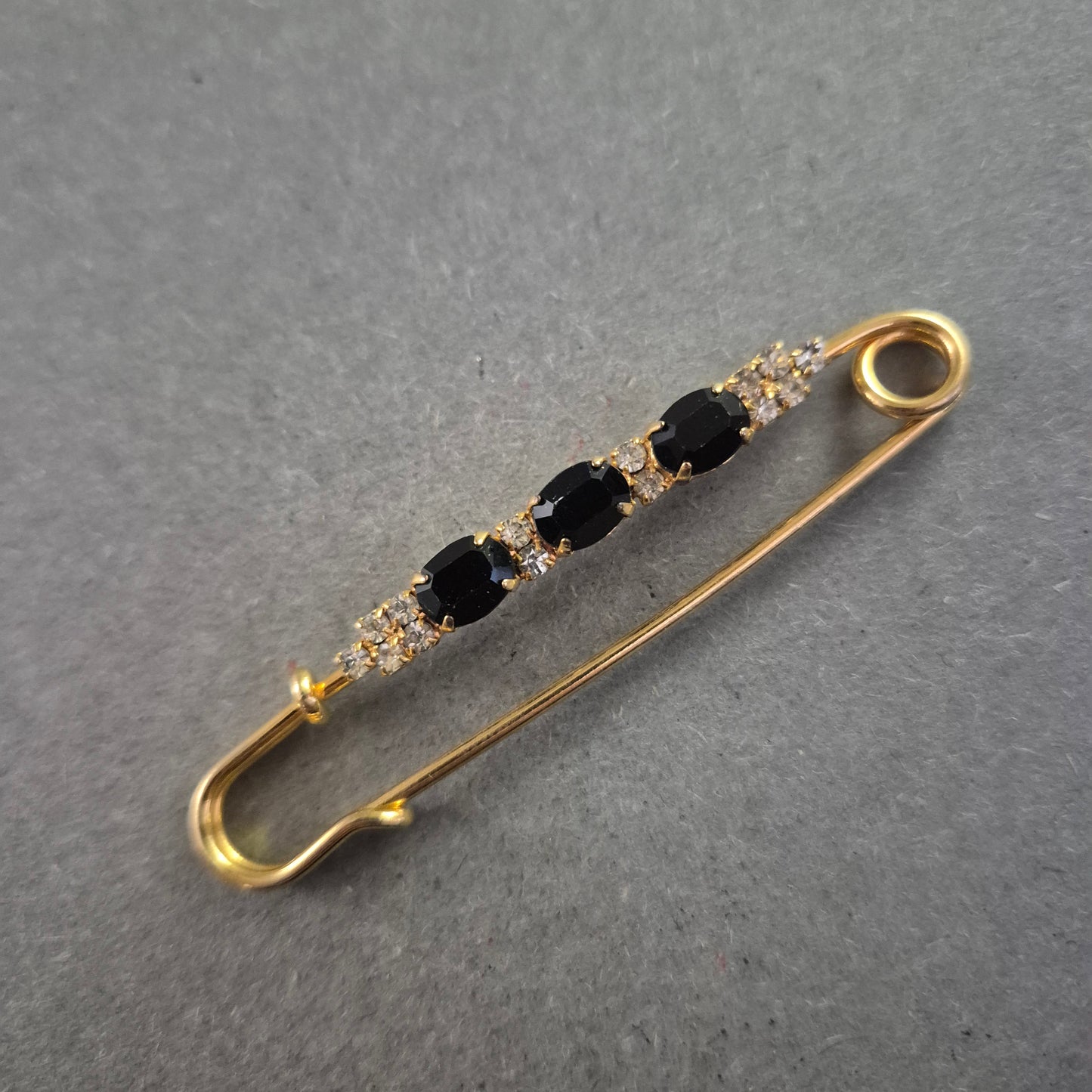 Elegante goldene Brosche – Sicherheitsnadel mit schwarzen Ziersteinen