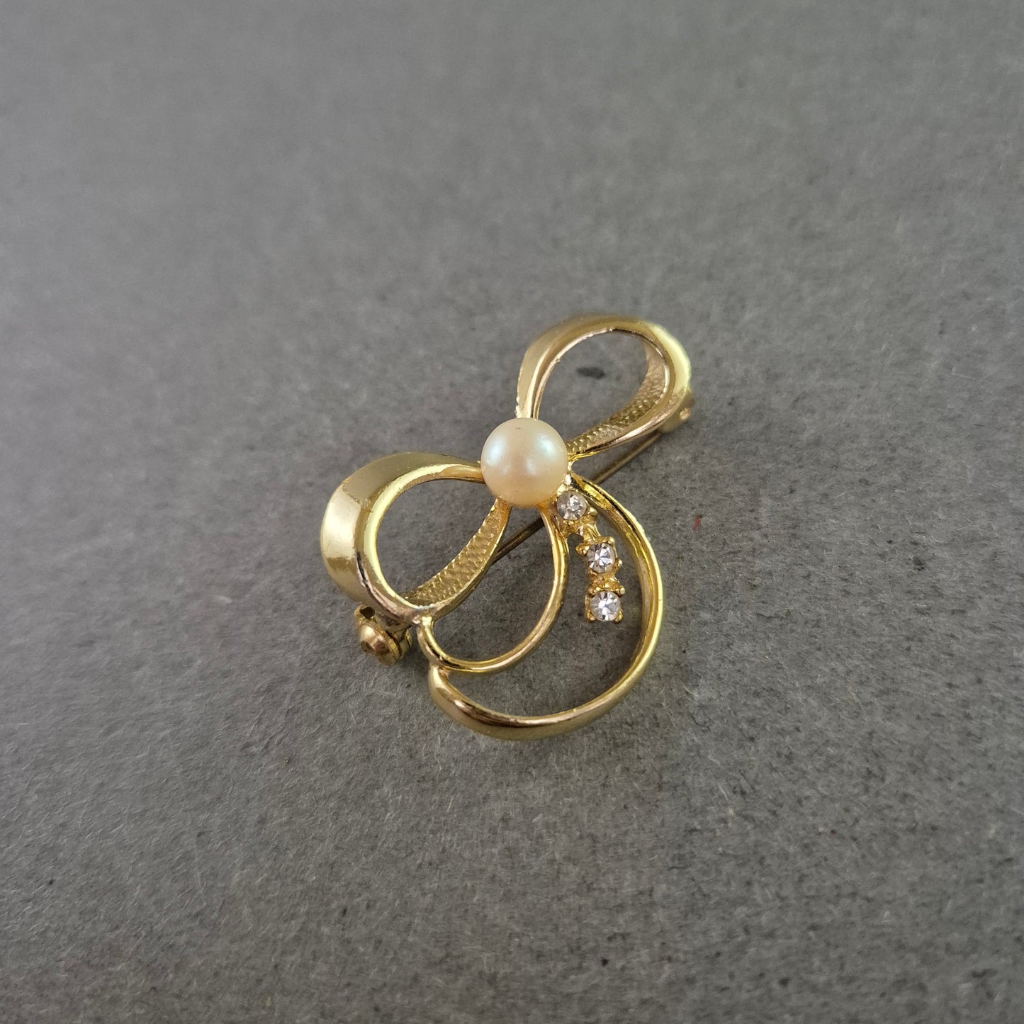 Zarte Brosche in Schleifenform mit Strass und Perlenimitat