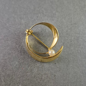Elegante goldfarbene Brosche mit Perle im modernen Design