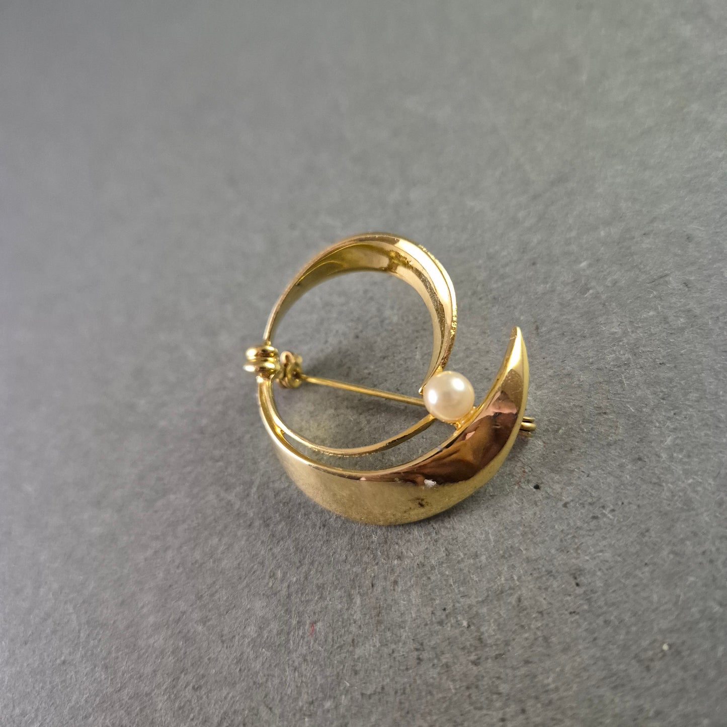 Elegante goldfarbene Brosche mit Perle im modernen Design