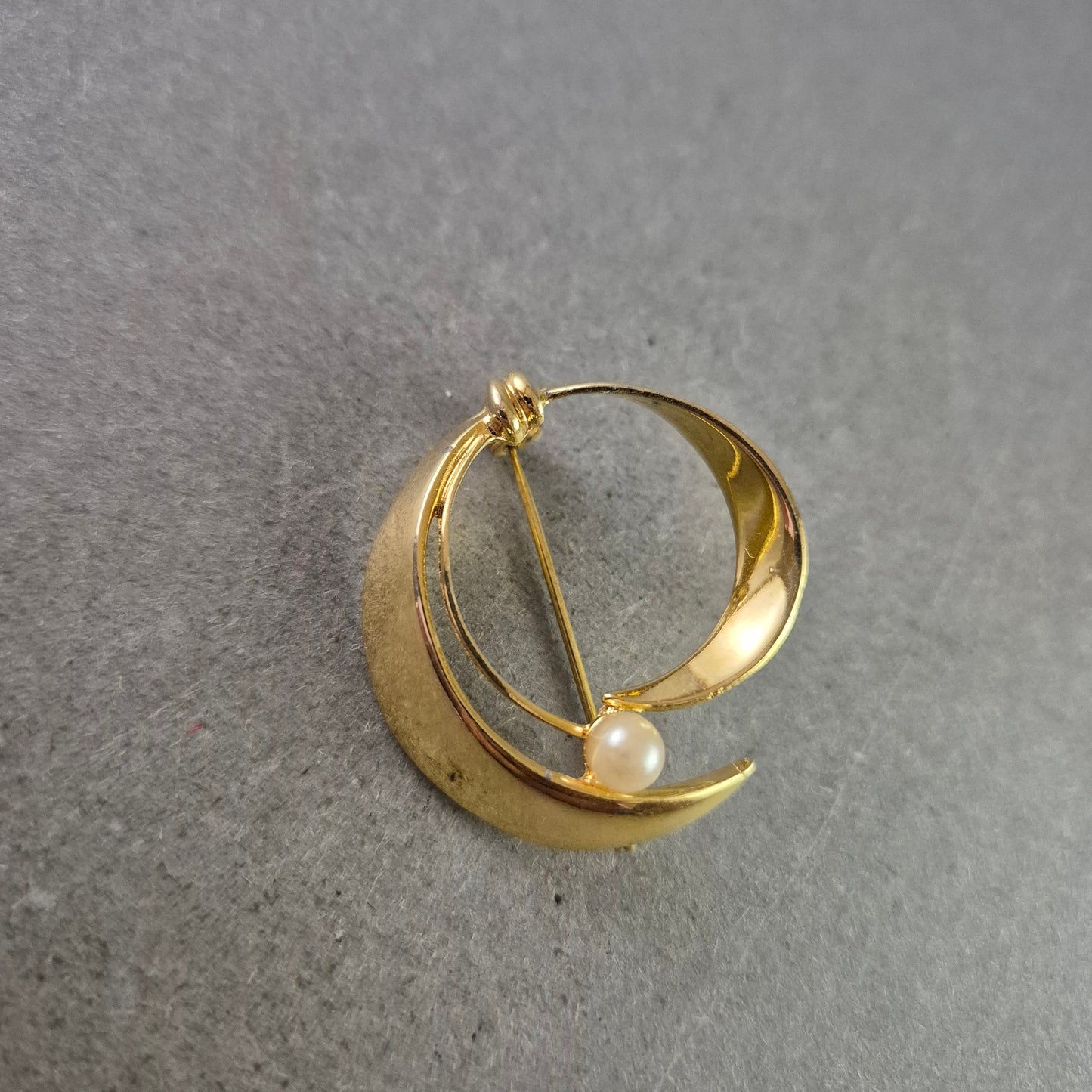 Elegante goldfarbene Brosche mit Perle im modernen Design