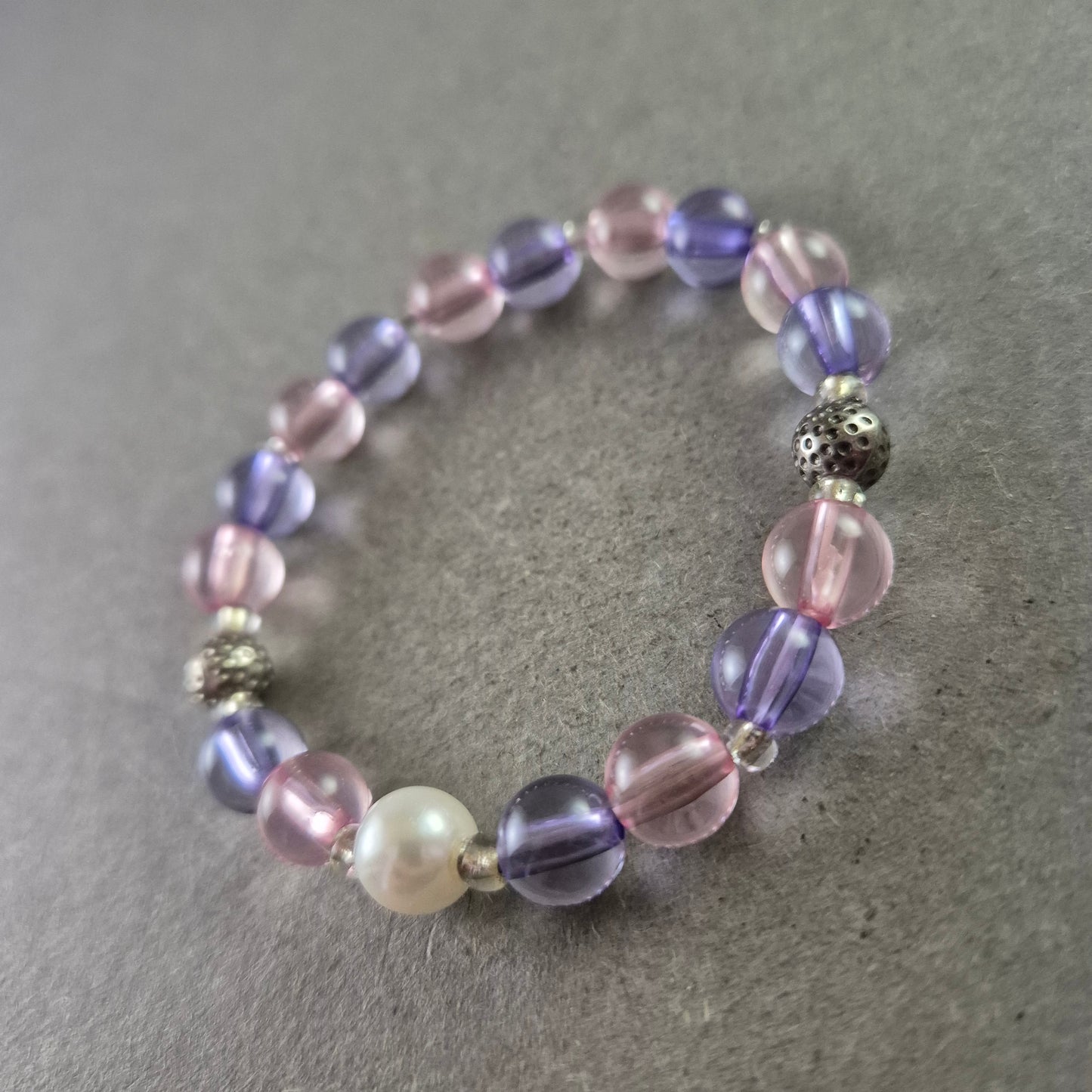 Elastisches Armband mit rosa und violetten Glasperlen