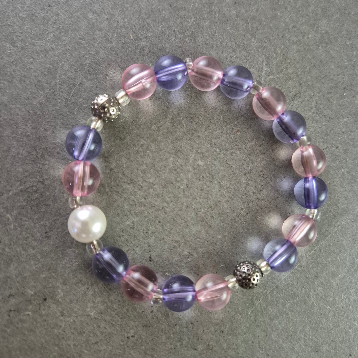 Elastisches Armband mit rosa und violetten Glasperlen