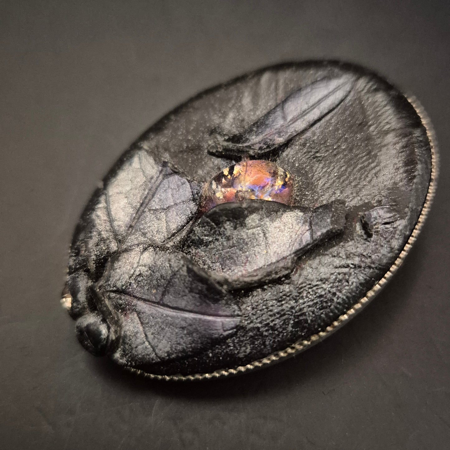 Elegante Brosche aus schwarzem Leder mit leuchtendem Cabochon