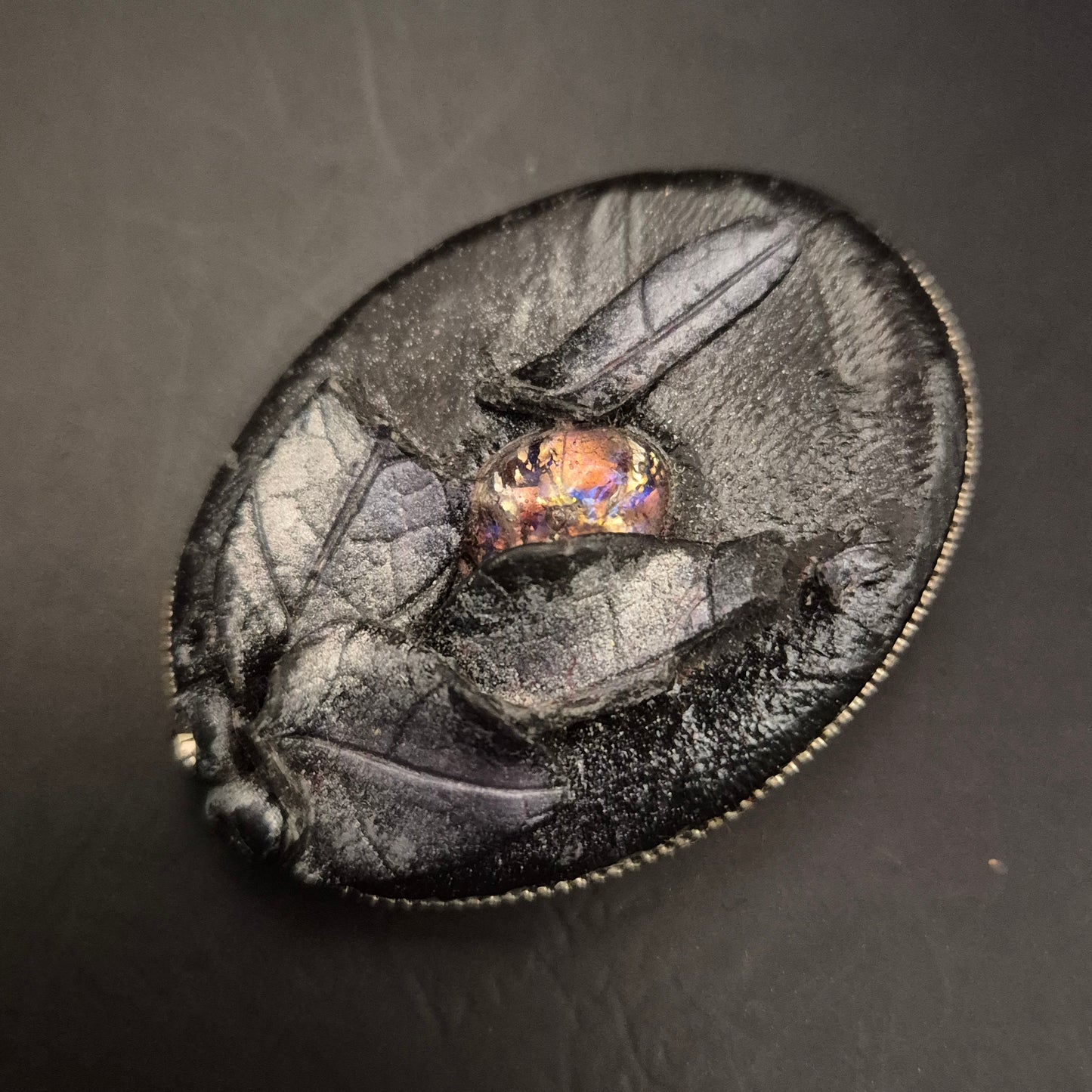 Elegante Brosche aus schwarzem Leder mit leuchtendem Cabochon