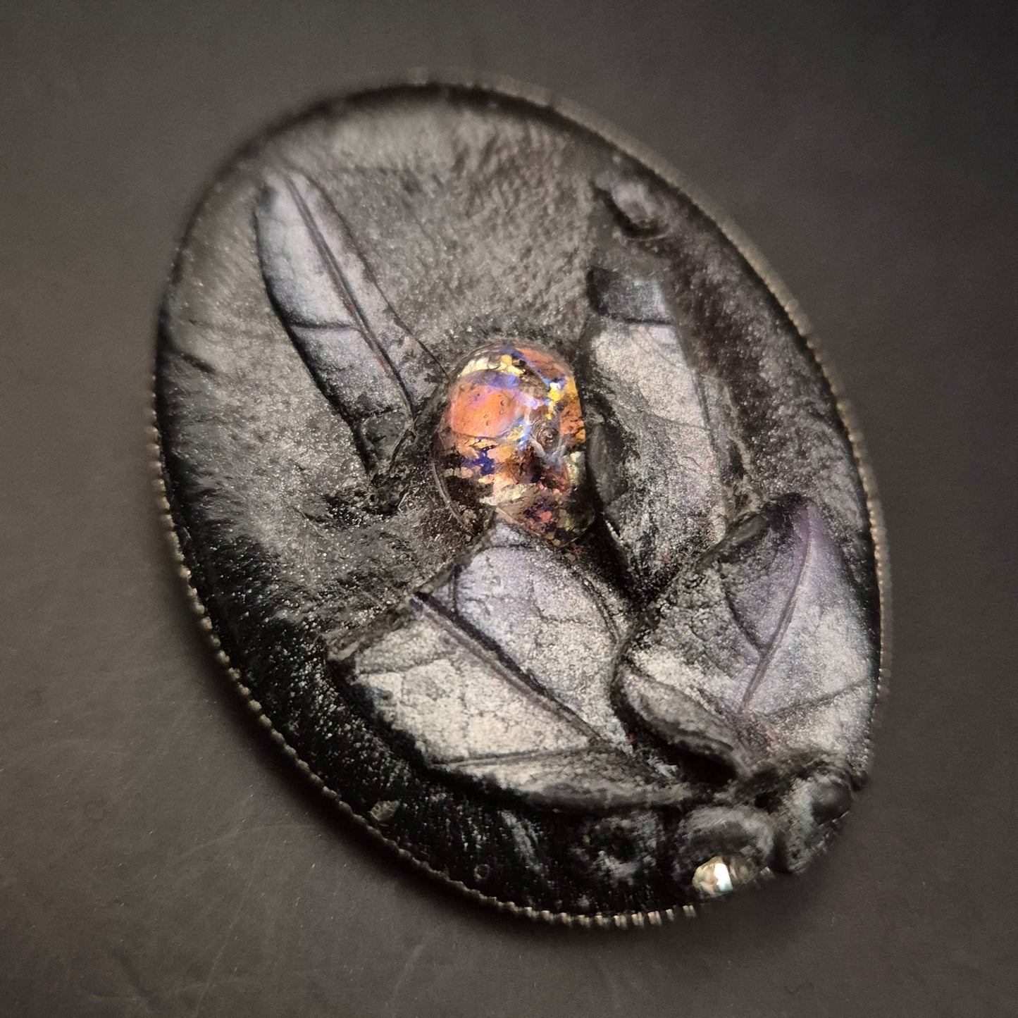 Elegante Brosche aus schwarzem Leder mit leuchtendem Cabochon