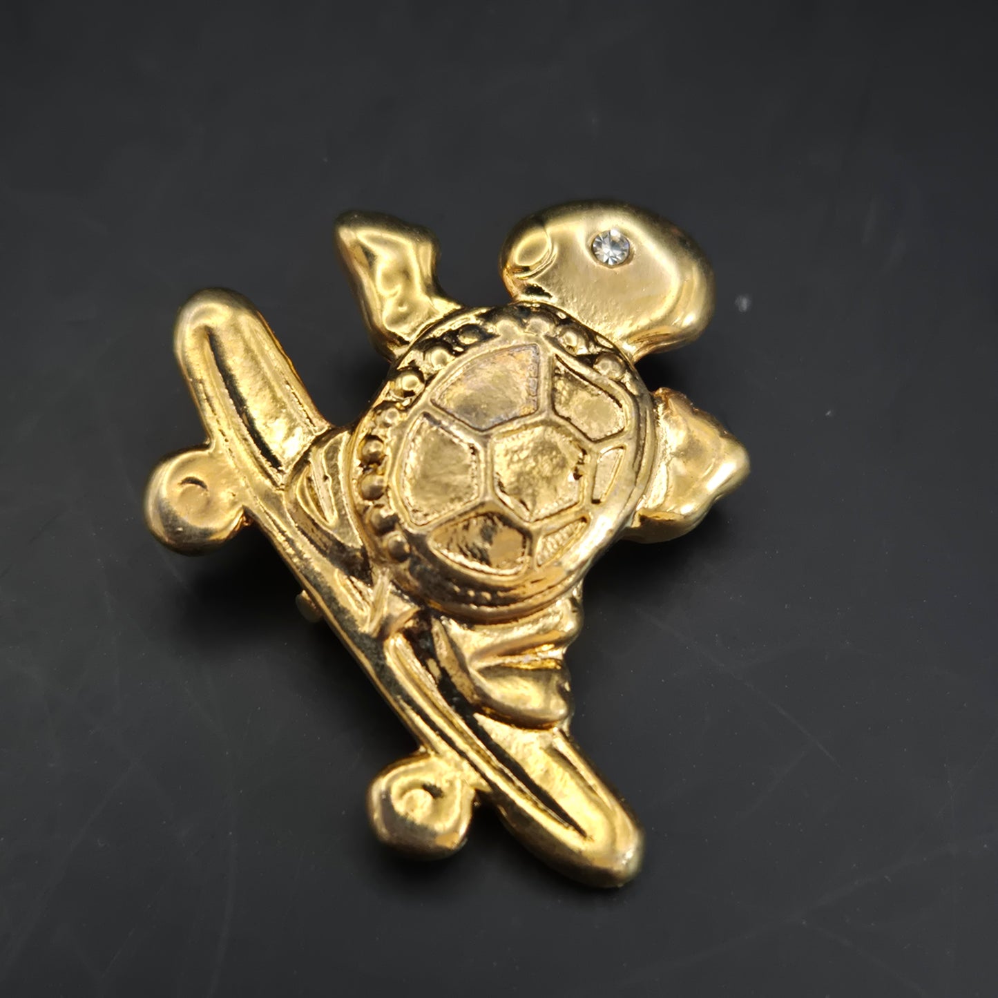 Verspielte Schildkröte auf Skateboard – Goldfarbene Brosche mit Kristall-Auge