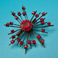 Vintage Starburst Brosche mit roten Strasssteinen in dunklem Metall
