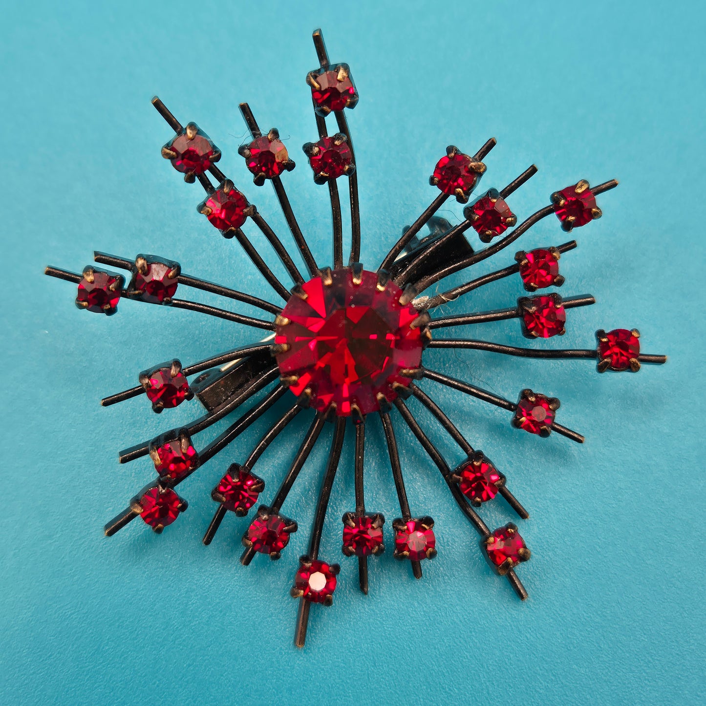 Vintage Starburst Brosche mit roten Strasssteinen in dunklem Metall