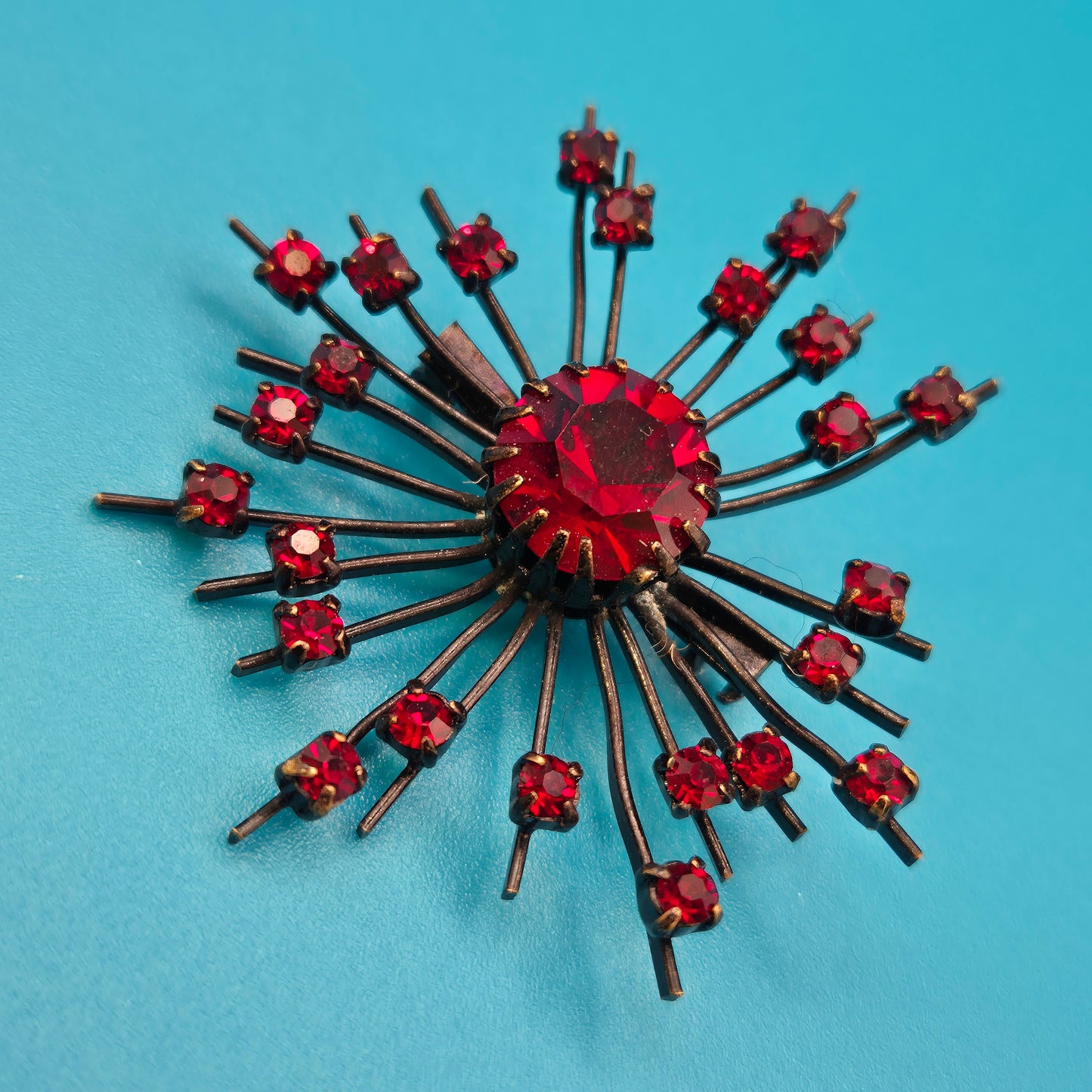 Vintage Starburst Brosche mit roten Strasssteinen in dunklem Metall