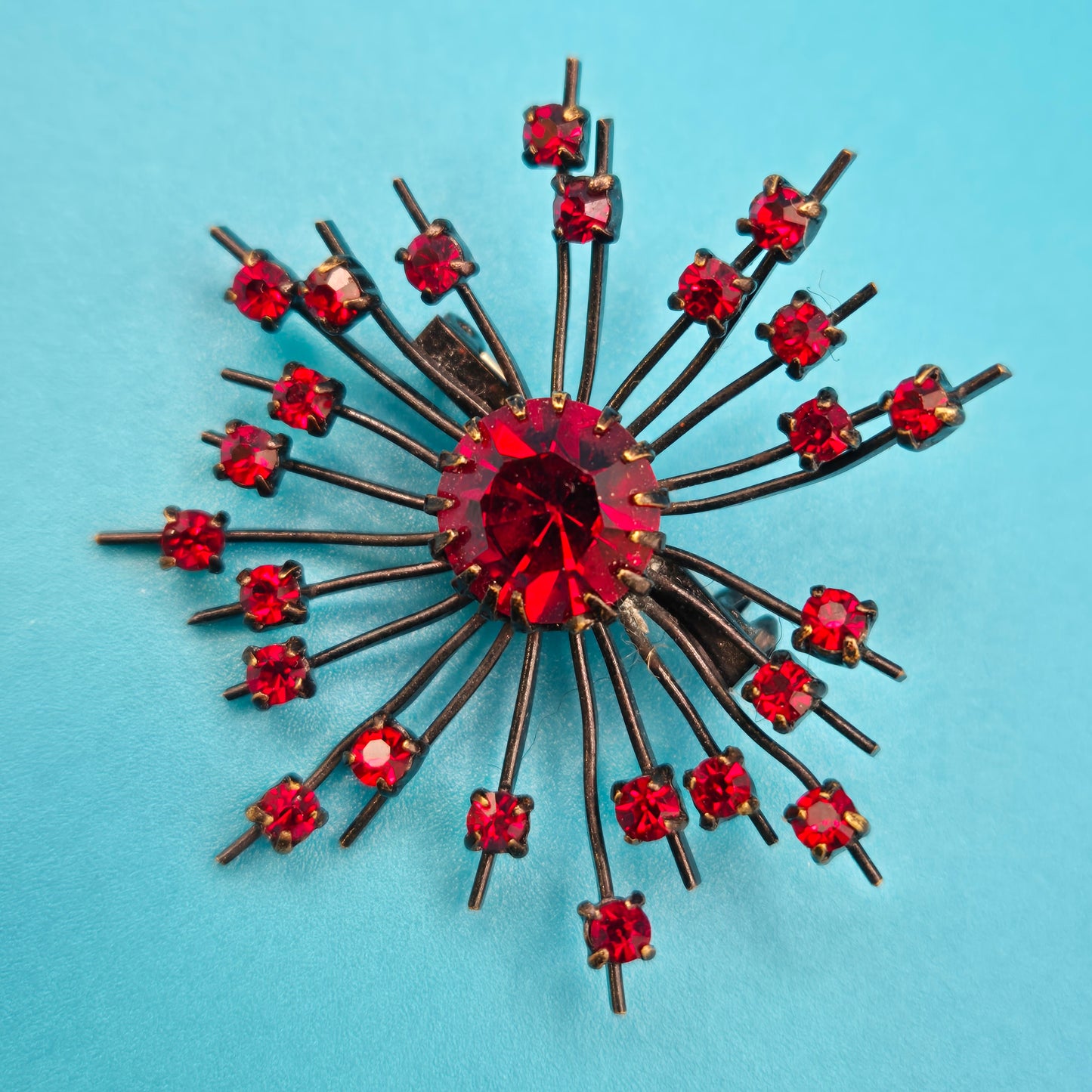 Vintage Starburst Brosche mit roten Strasssteinen in dunklem Metall
