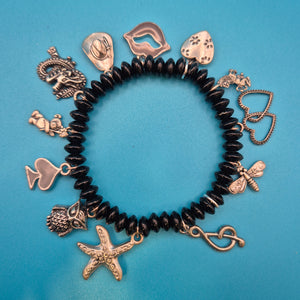 Verspieltes Vintage Charm-Armband mit schwarzen Perlen und Anhängern