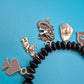Verspieltes Vintage Charm-Armband mit schwarzen Perlen und Anhängern