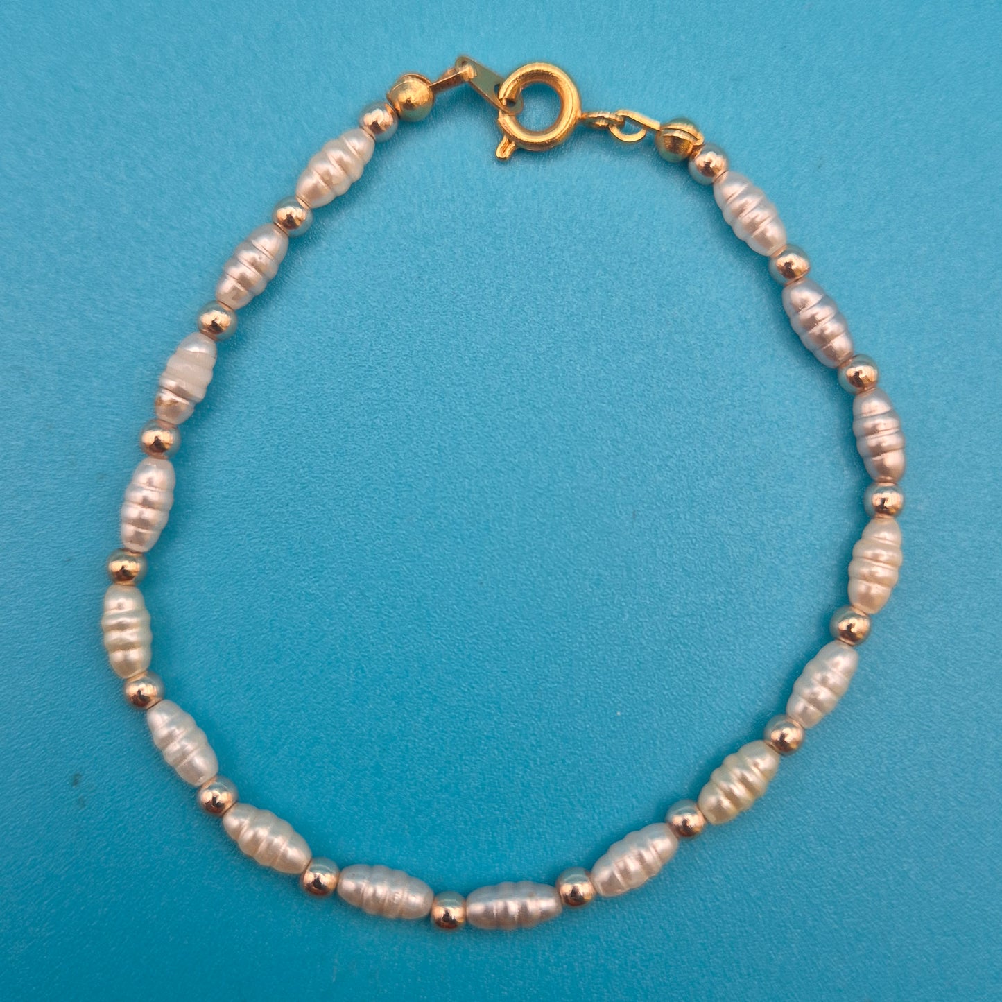 Elegantes Vintage-Armband mit weißen Reisperlen und goldenen Elementen