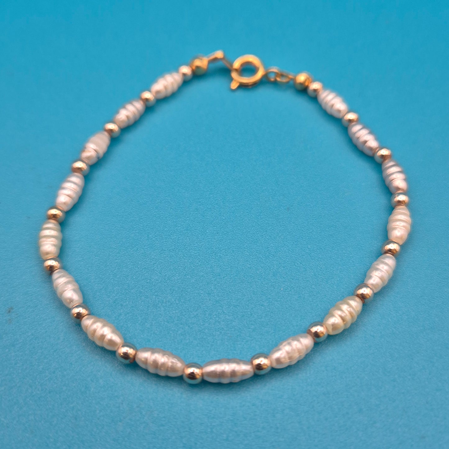 Elegantes Vintage-Armband mit weißen Reisperlen und goldenen Elementen