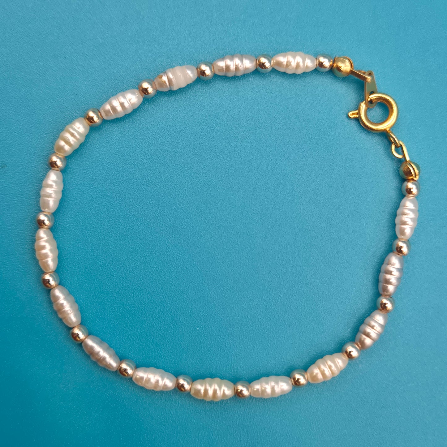 Elegantes Vintage-Armband mit weißen Reisperlen und goldenen Elementen