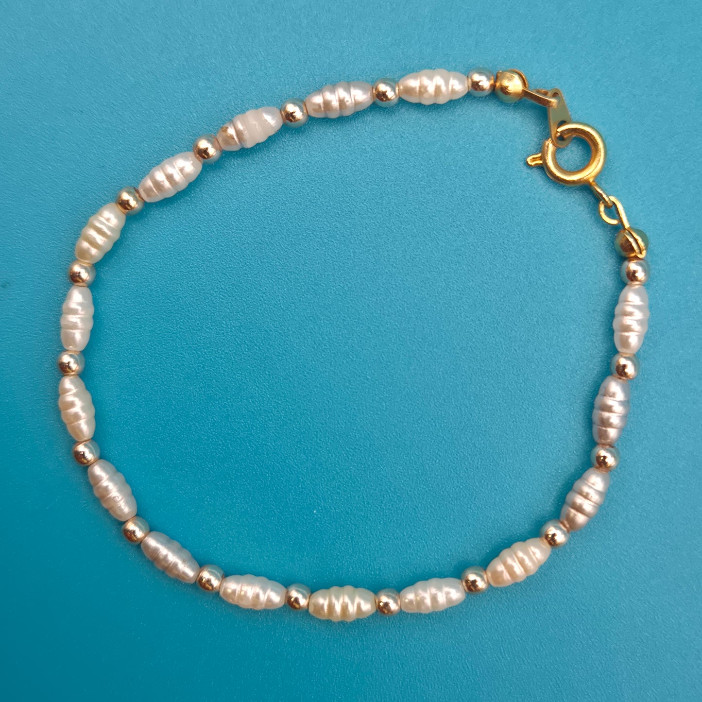 Elegantes Vintage-Armband mit weißen Reisperlen und goldenen Elementen
