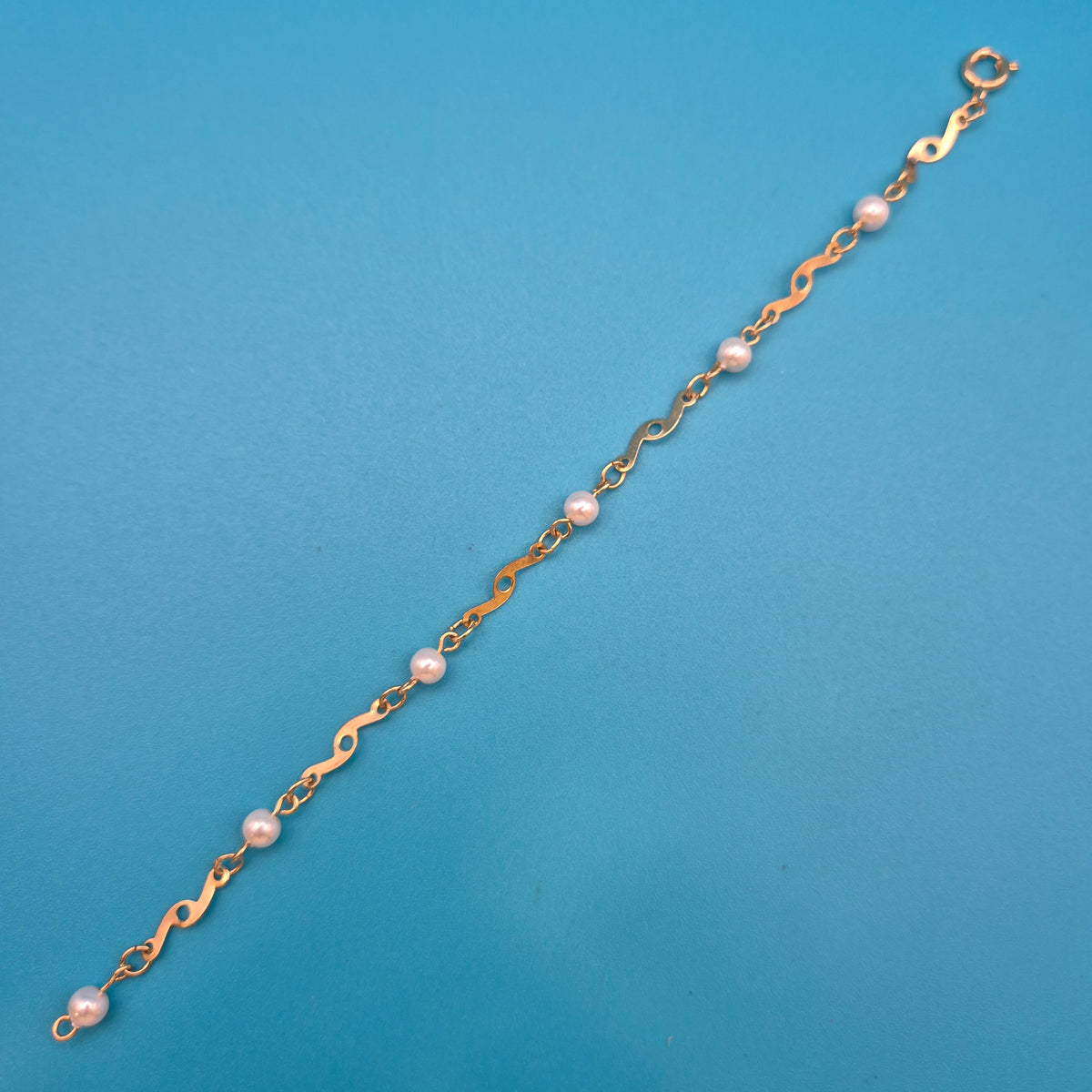 Elegantes Vintage-Armband mit Ziergliedern und weißen Perlen Goldfarben