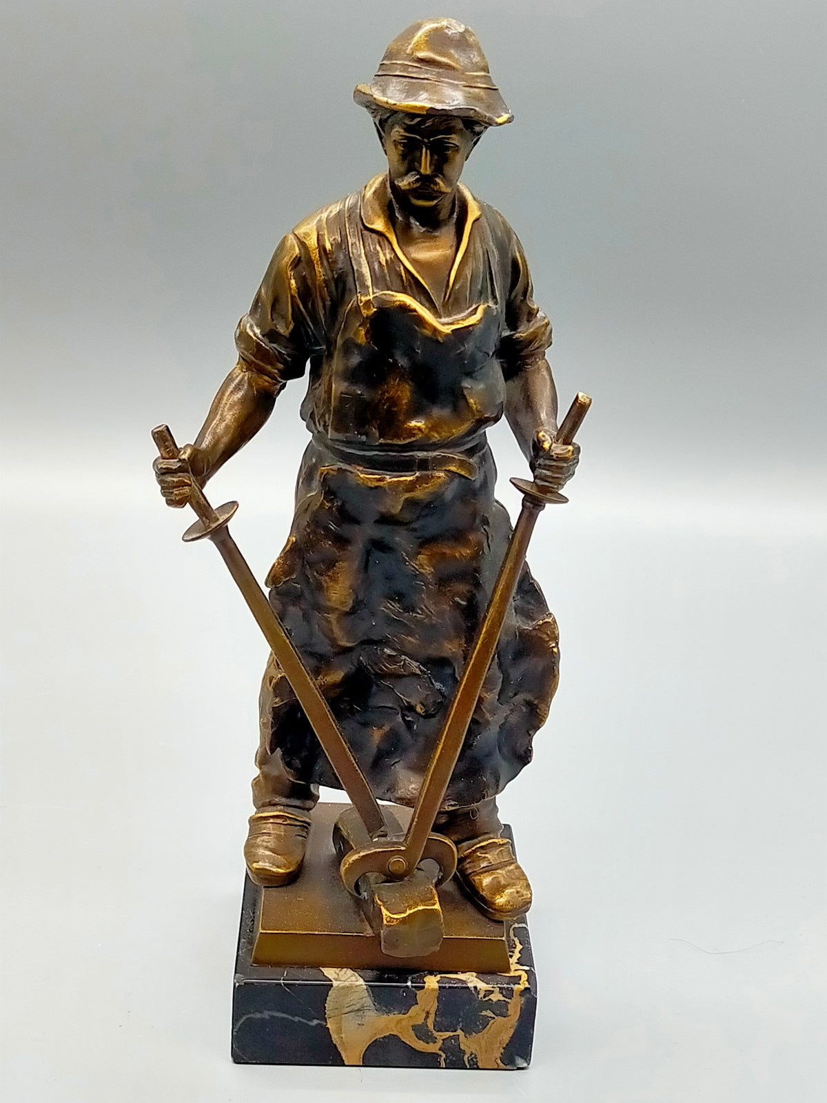 Antike Skulptur – Schmied mit Amboss auf Marmorsockel