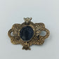 Antik anmutende Brosche mit dunkelblauem Stein