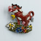 Farbenfrohe Kuh-Brosche mit Blumenmotiv