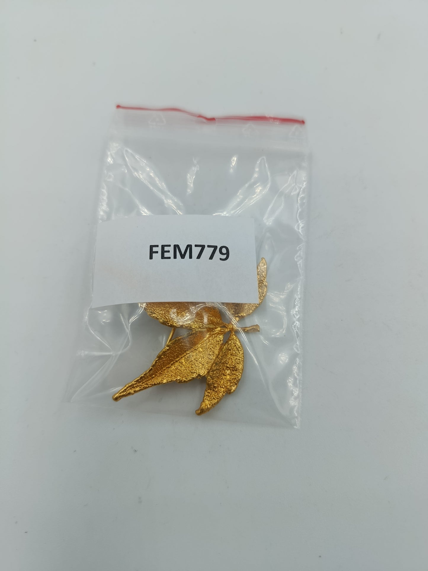 Goldfarbene Brosche in Blattform mit strukturierter Oberfläche