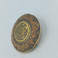 Runde goldfarbene Brosche mit orientalischem Muster
