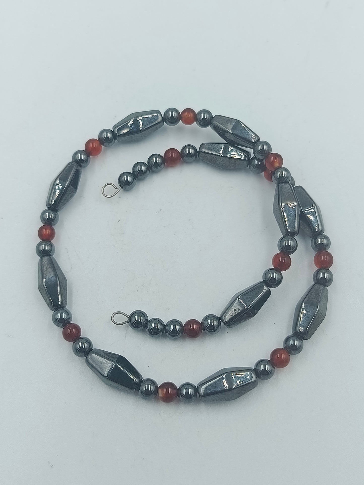 Elastisches Hämatit Armband mit roten Zierperlen