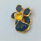 Goldfarbene Blütenbrosche mit schwarzer Emaille