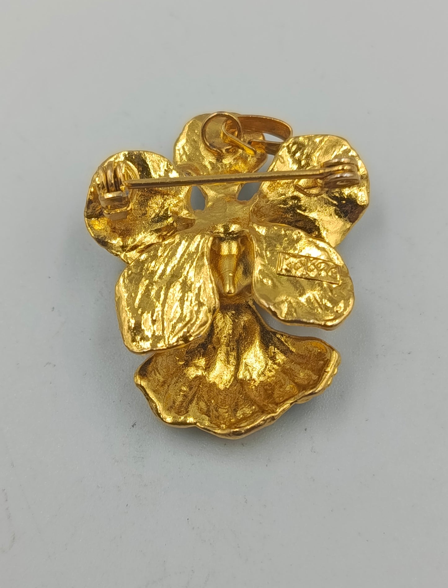 Goldfarbene Blütenbrosche mit schwarzer Emaille