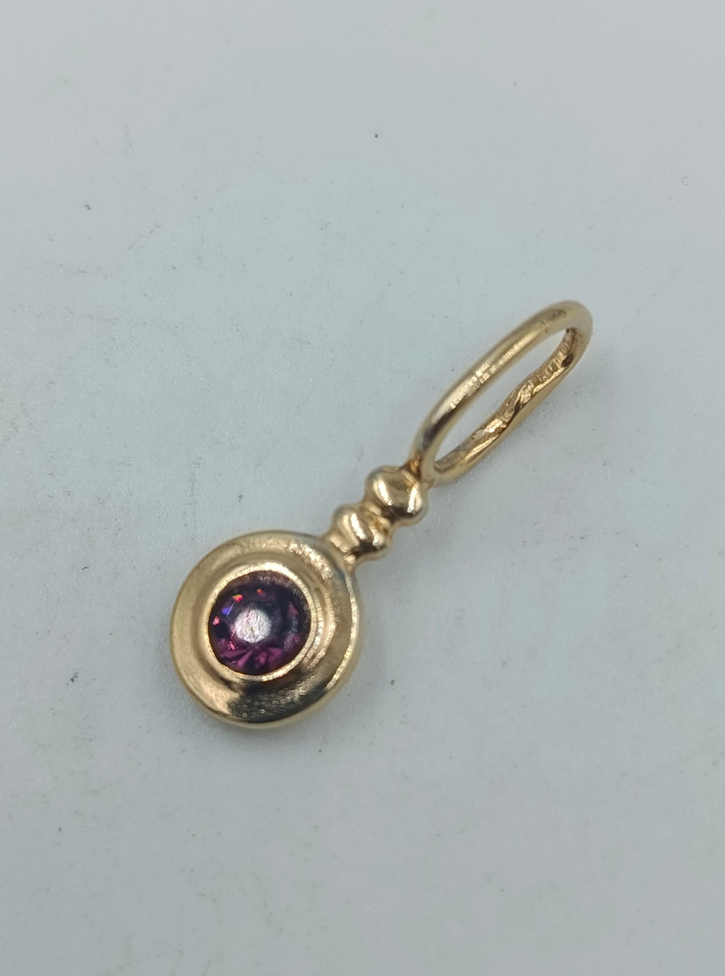 Goldfarbener Anhänger mit violettem Stein rund elegant