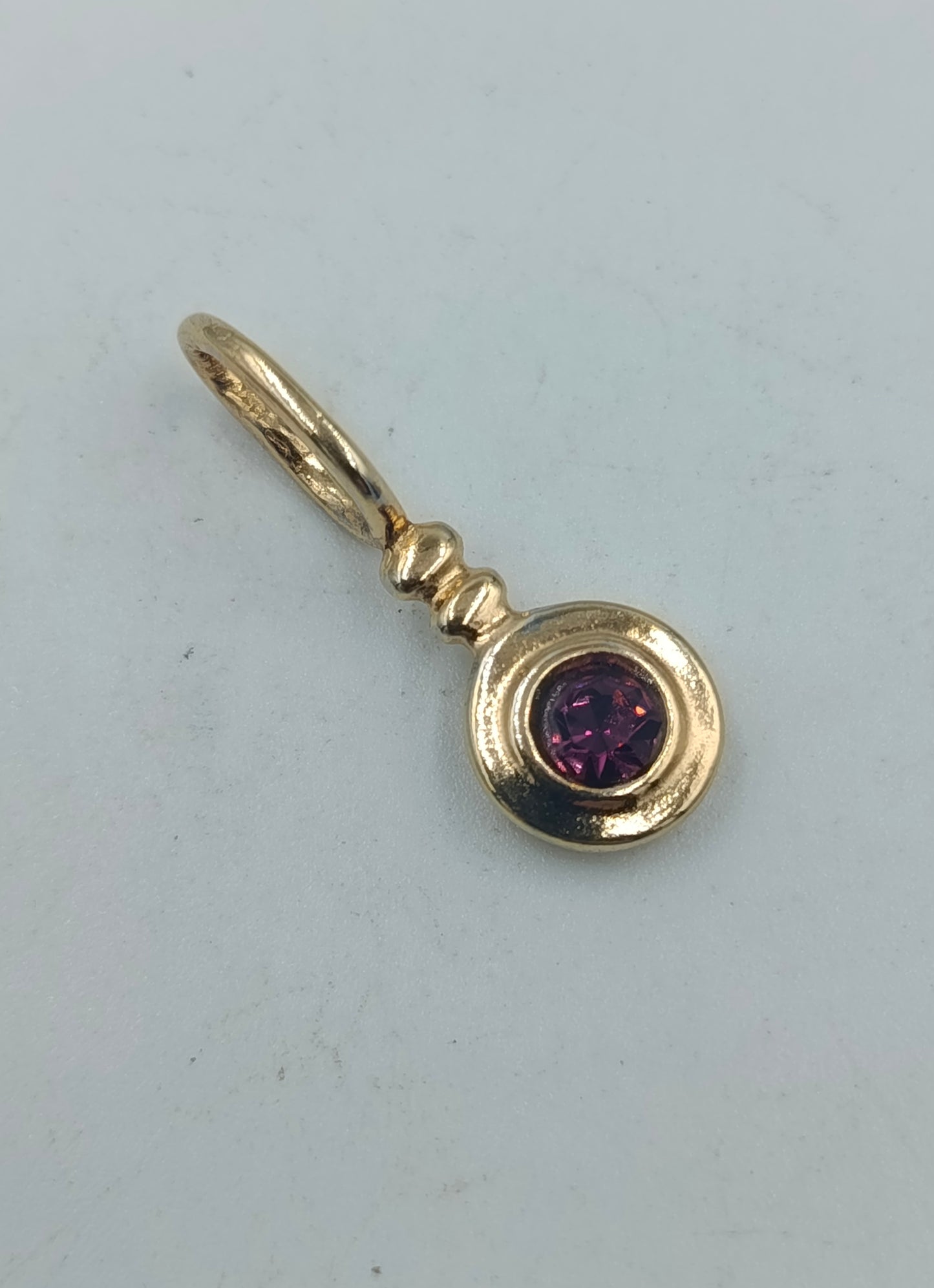 Goldfarbener Anhänger mit violettem Stein rund elegant