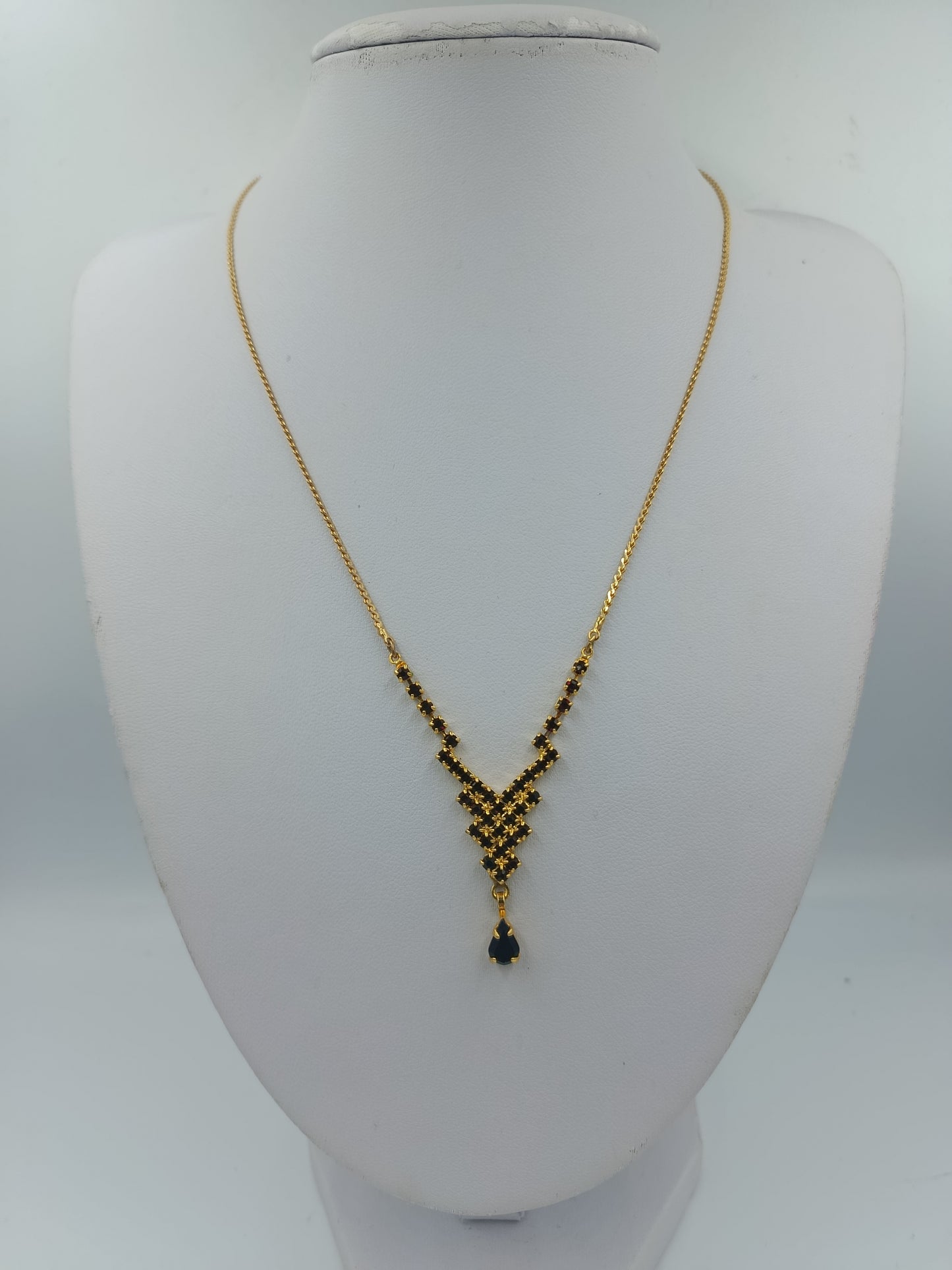 Goldfarbene Halskette mit schwarzen Steinen und Tropfenanhänger
