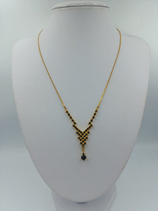 Goldfarbene Halskette mit schwarzen Steinen und Tropfenanhänger