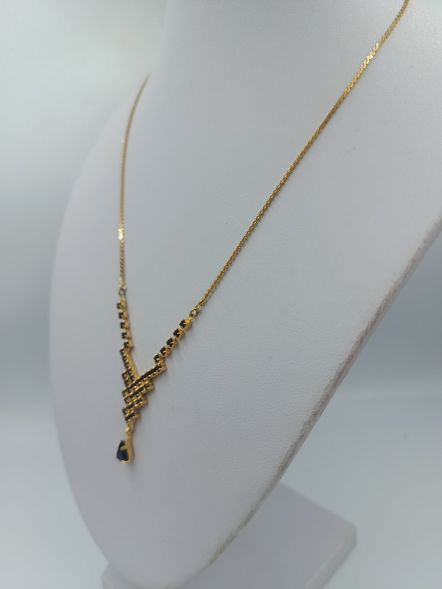 Goldfarbene Halskette mit schwarzen Steinen und Tropfenanhänger