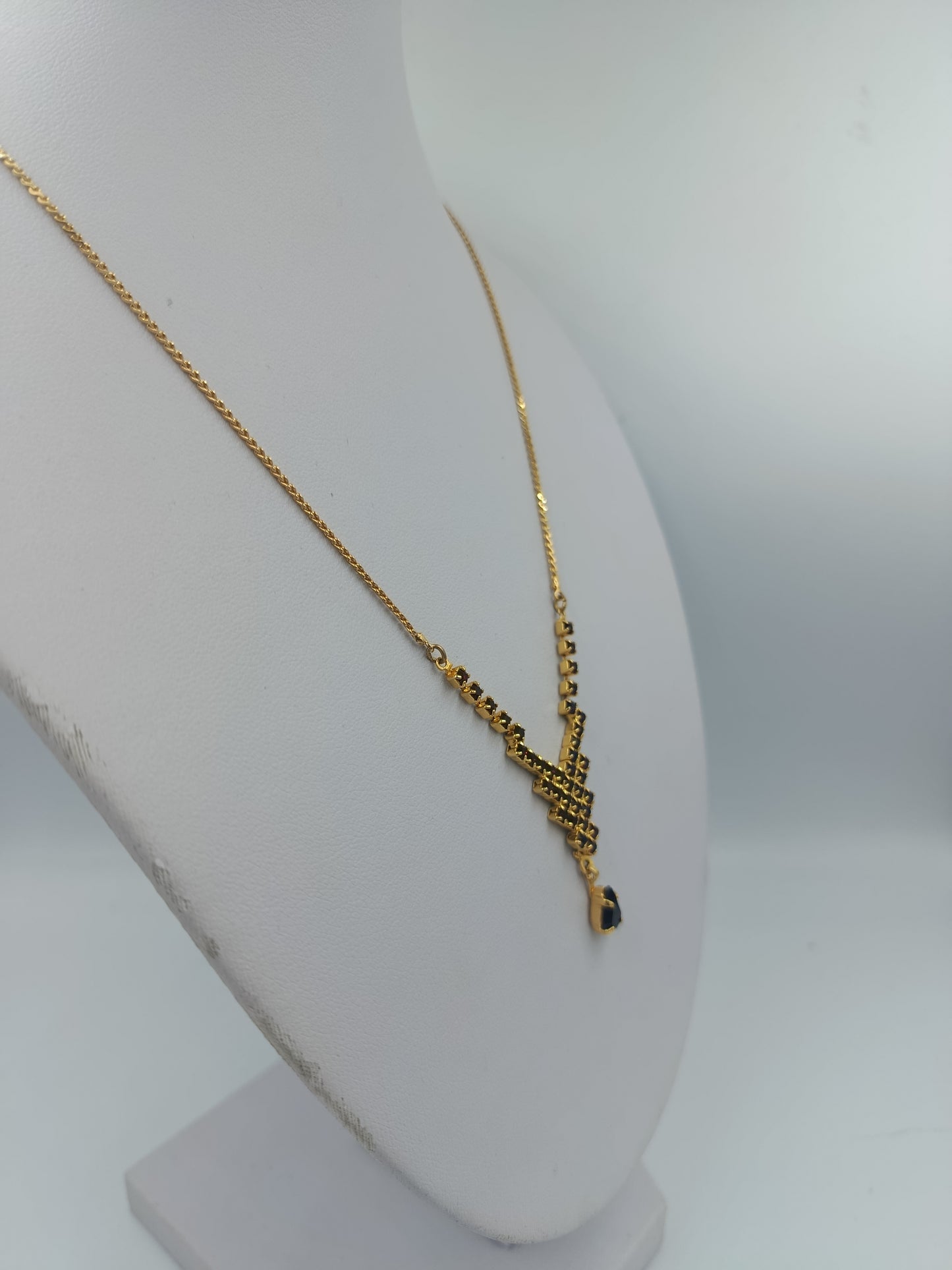 Goldfarbene Halskette mit schwarzen Steinen und Tropfenanhänger