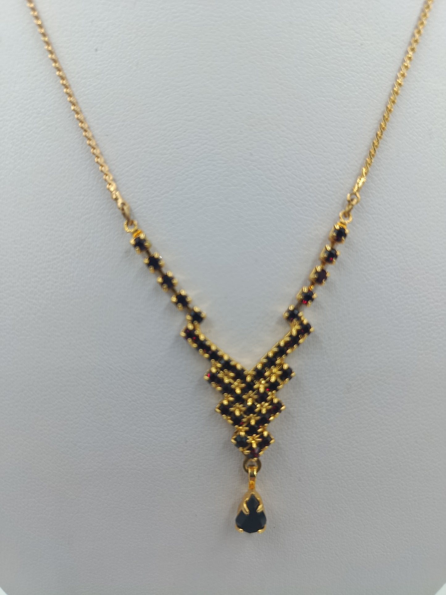 Goldfarbene Halskette mit schwarzen Steinen und Tropfenanhänger