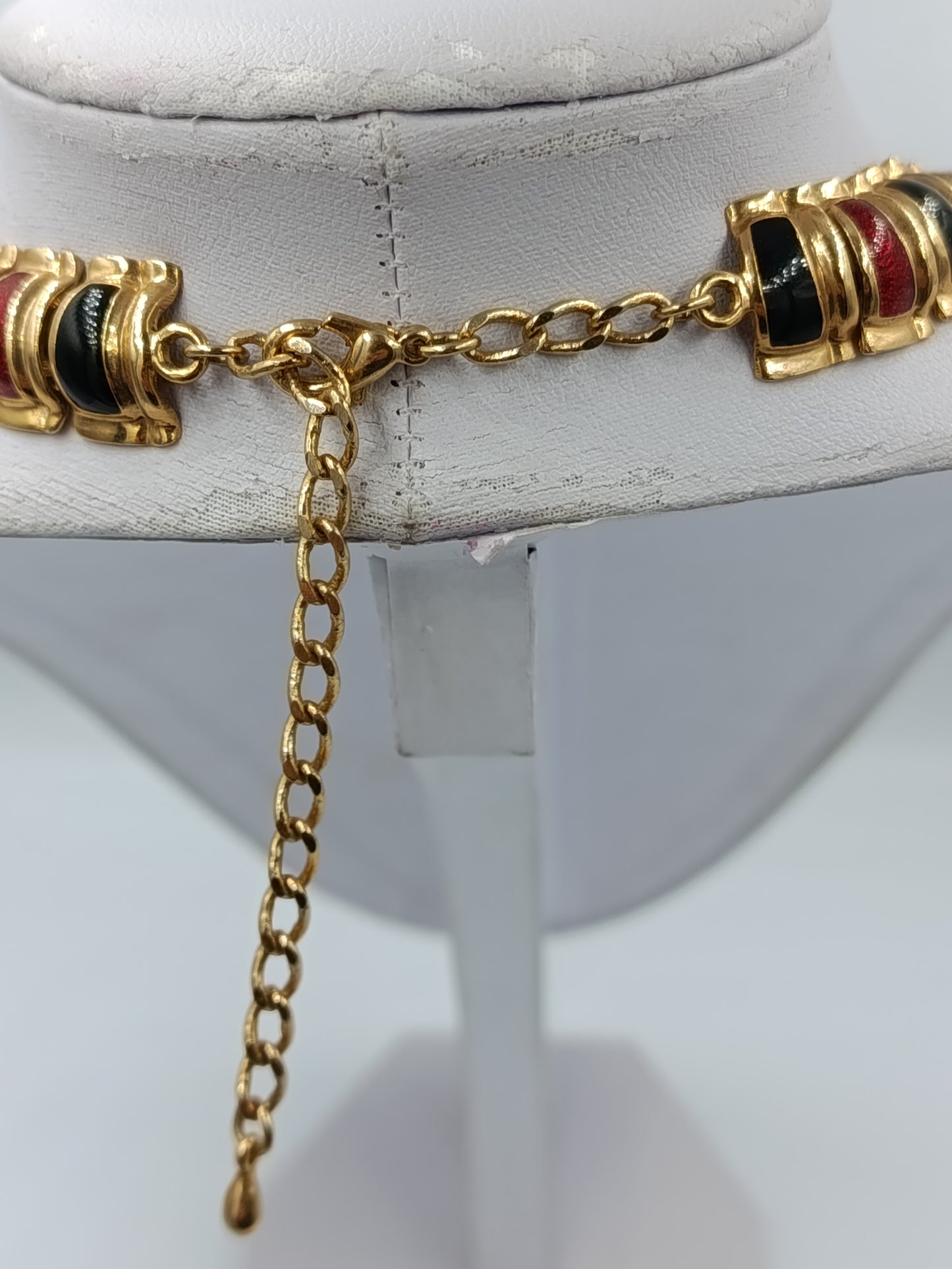Halskette mit goldfarbenen Gliedern und rot schwarzen Emaille Elementen