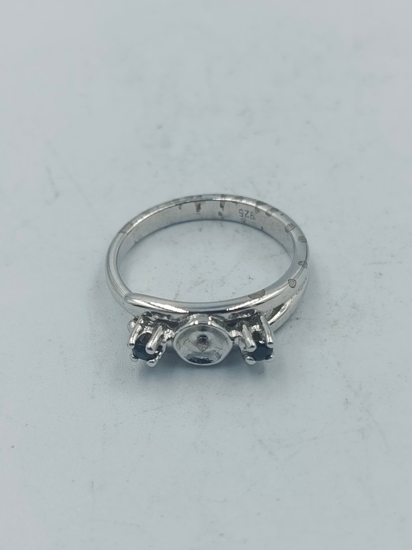 Eleganter Silberring mit dunklen Seitensteinen und mittiger Fassung